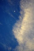 Half moon with clouds covering blue sky