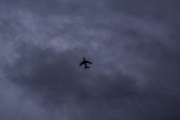 Plane flying just below the grey and dark stormy clouds