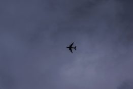 Plane flying just below the grey and dark stormy clouds