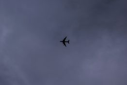 Plane flying just below the grey and dark stormy clouds