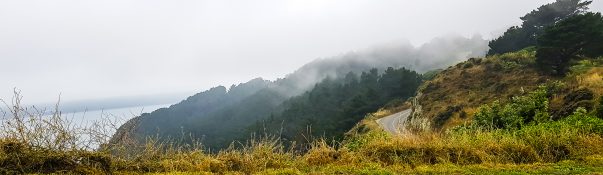 Road going uphill leading to a foggy mountain