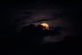 Moon hiding behind clouds and creating beautiful patterns on the dark clouds