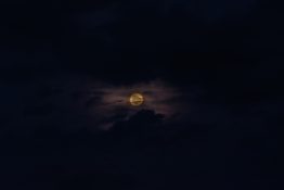 Moon hiding behind clouds and creating beautiful patterns on the dark clouds