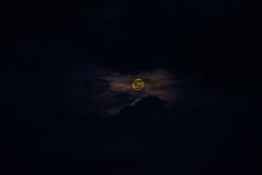 Moon hiding behind clouds and creating beautiful patterns on the dark clouds