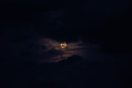 Moon hiding behind clouds and creating beautiful patterns on the dark clouds