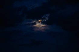 Moon hiding behind clouds and creating beautiful patterns on the dark clouds