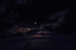 Moon hiding behind clouds and creating beautiful patterns on the dark clouds