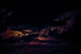 Moon hiding behind clouds and creating beautiful patterns on the dark clouds