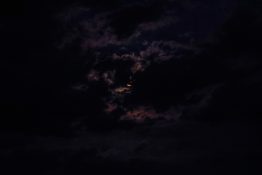 Moon hiding behind clouds and creating beautiful patterns on the dark clouds