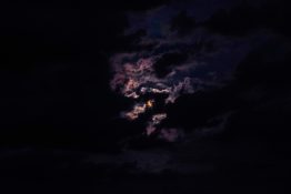 Moon hiding behind clouds and creating beautiful patterns on the dark clouds