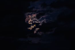 Moon hiding behind clouds and creating beautiful patterns on the dark clouds