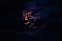 Moon hiding behind clouds and creating beautiful patterns on the dark clouds