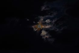 Moon hiding behind clouds and creating beautiful patterns on the dark clouds