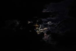 Moon hiding behind clouds and creating beautiful patterns on the dark clouds