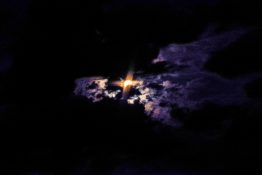 Moon hiding behind clouds and creating beautiful patterns on the dark clouds