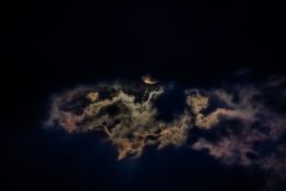 Moon hiding behind clouds and creating beautiful patterns on the dark clouds