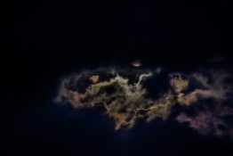 Moon hiding behind clouds and creating beautiful patterns on the dark clouds