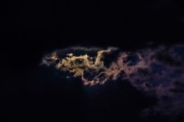 Moon hiding behind clouds and creating beautiful patterns on the dark clouds