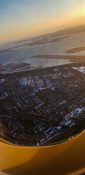 Looking at buildings and homes from a planes window as it fly's over a residential area as the sun sets