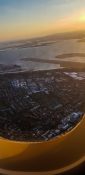 Looking at buildings and homes from a planes window as it fly's over a residential area as the sun sets