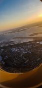 Looking at buildings and homes from a planes window as it fly's over a residential area as the sun sets