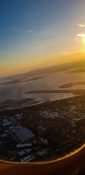 Looking at buildings and homes from a planes window as it fly's over a residential area as the sun sets