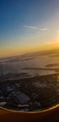 Looking at buildings and homes from a planes window as it fly's over a residential area as the sun sets