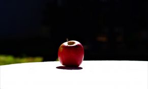 An apple left out in the sun on a outdoor table