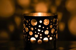 Candle lit in a candle holder creating beautiful shadows.