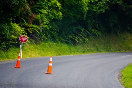 Stop road sign and two orange traffic cones placed on the road