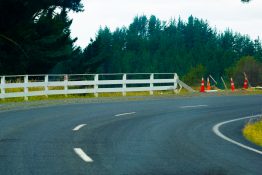 on a bend passing a white fence and some road side cones