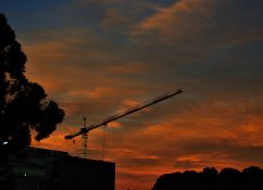 Crane at a construction site late in the afternoon with the back drop of evening colorful clouds